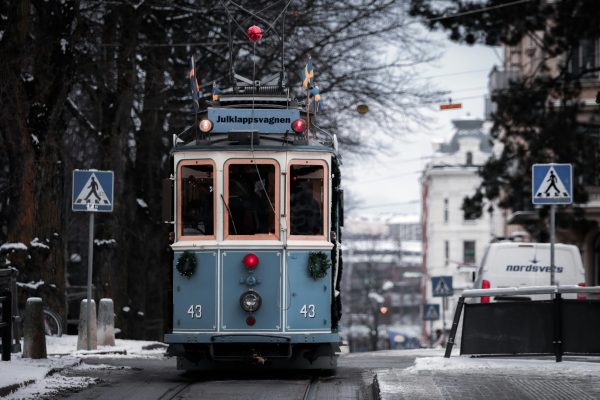 A classic blue tram makes its way through a snowy street in Gothenburg, Sweden on a winter day.
